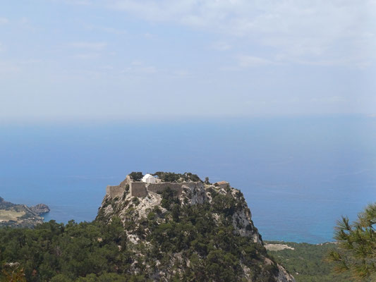 Auf dem Foto ist eine auf einem Felsen gebaute Burg zu sehen. Im Hintergrund der Burg ist das Meer und ein hellblauer leicht bewölkter Himmel zu sehen.