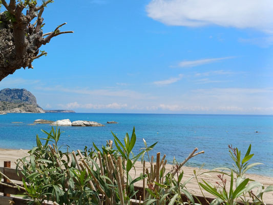 Auf dem Foto ist im Hintergrund das türkisgesprenkelte Meer zu sehen und im Vordergrund der Strand.