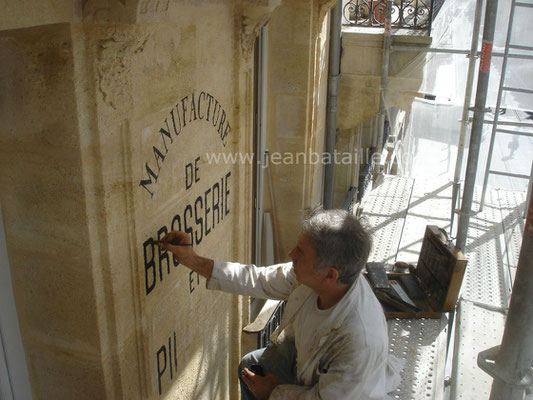 Reproduction du nom de la boutique sur mur en pierre