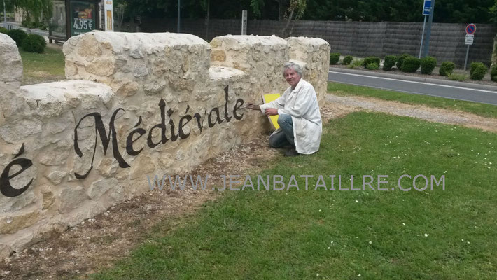 Lettres peintes sur mur en moellons