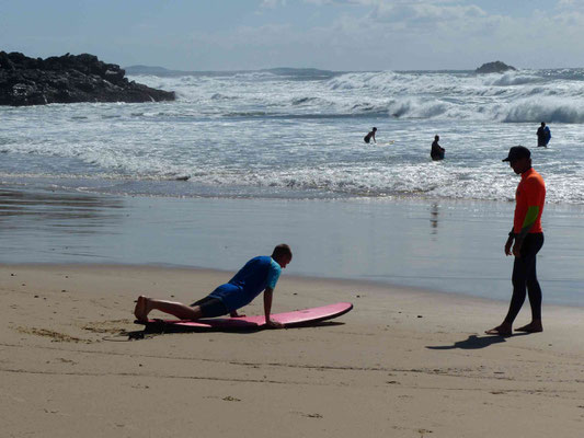 Surflehrer gibt Neuling Anweisungen (aller Anfang ist schwer)