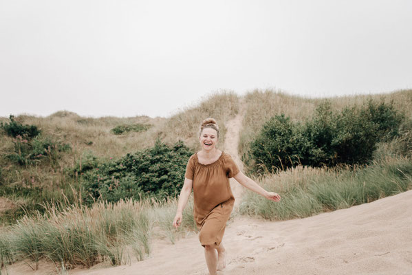 Szilvia Rölke rennt barfuß lachend über einen Sandstrand.