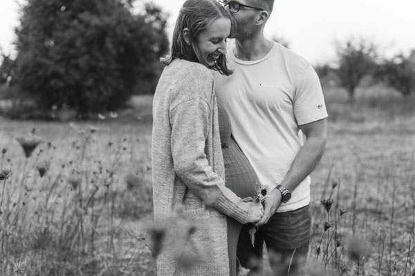 Lachendes Paar bei einem Babybauch-Shooting im Blumenfeld in Rockenberg.