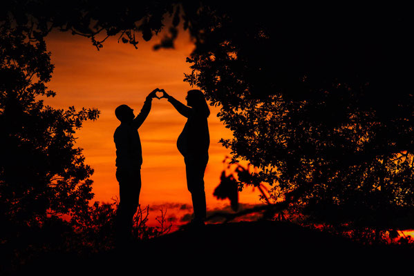 Silhouette von werdenden Eltern im Sonnenuntergang bei einem Babybauchshooting.