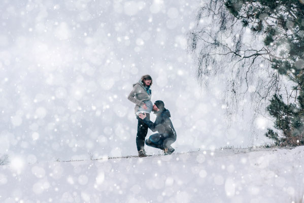 Schwangerschaftsfotografie im Schnee: Vater küsst den Babybauch.