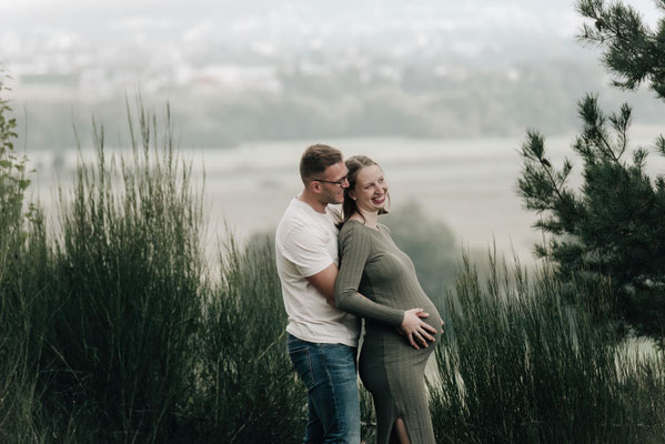 Babybauchshooting in der Wetterau: Ein Paar umarmt liebevoll den Babybauch bei einem herbstlichen Outdoorshooting.
