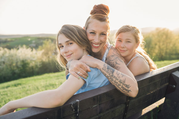 Glückliche Familie sitzt lächelnd auf einer Bank in Bad Nauheim, fotografiert von Familienfotografin.