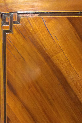 Aan dit detail van een pruimenhouten kast is goed te zien dat het fineer is gescheurd en dat er stukjes ontbreken.