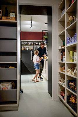 Großzügiger Vorratsraum mit Regalsystem, Blick in moderne Küche, Vater und Tochter beim gemeinsamen Kochen – praktische Stauraumlösung für Familienküchen.