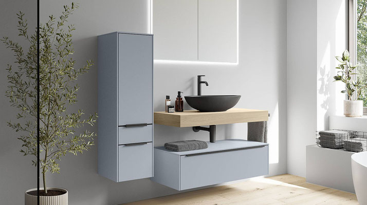 Modernes Badezimmer mit hellblauen Hängeschränken, Holz-Waschtisch, rundem Aufsatzwaschbecken und stilvoller Deko – zeitgemäßes Bad-Design mit viel Stauraum und natürlichem Licht.