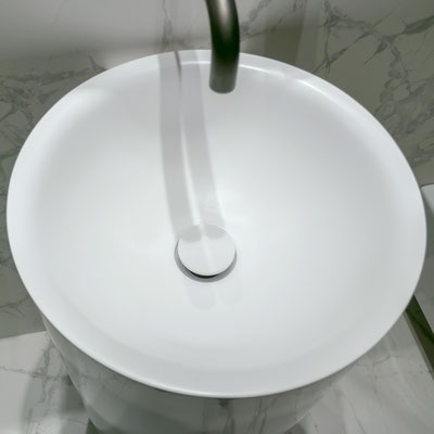 Round conic washbasin hanging on a wall fabricated from white solid surface
