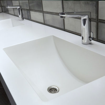 Hanging bathroom vanity with two integrated washbasins at a shopping cetre WC fabricated from Corian Designer White / fabricator: Gforma
