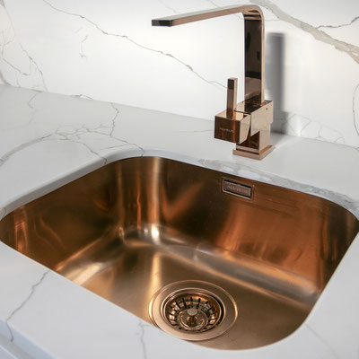 Copper kitchen sink integrated into engineered quartz countertop 
