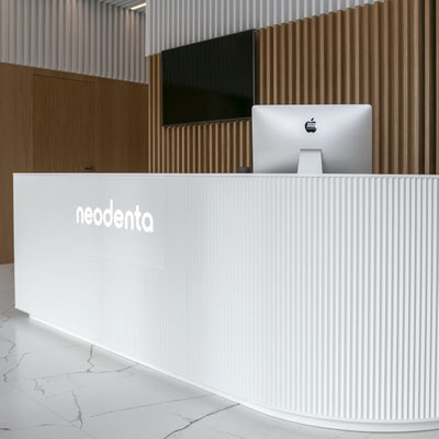Dental clinic reception desk with glowing logo fabricated from acrylic stone 