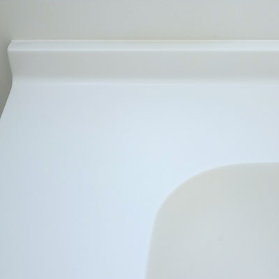 Medical sink with low splash guard made from white solid surface
