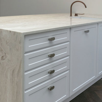White kitchen island clad in cream coloured solid surface with integrated sink 
