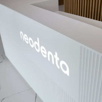 Dental clinic reception desk made from white acrylic stone with translucent logo 