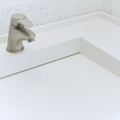 White minimalistic acrylic solid surface washbasin integrated in the bathroom vanity