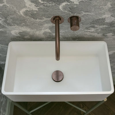 White sink fabricated from Corian Designer White solid surface placed on metal legs 
