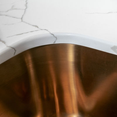 Quartz worktop edge where it joins the copper sink