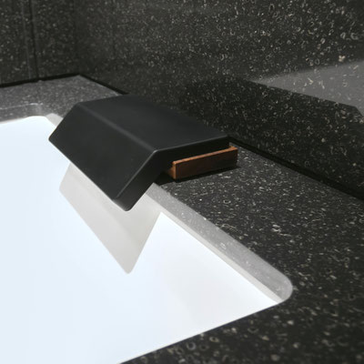 White porcelain bathtub clad in black Corian joint seamlessly with splashwalls from the same solid surface 