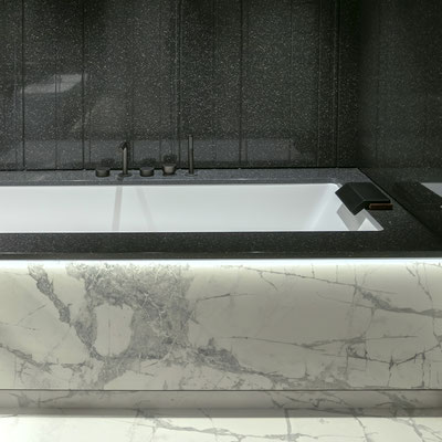 Bathtub fitted in a black solid surface frame with white ceramic sides 