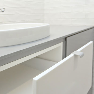 Laundry stand for washing machine topped with grey solid surface, with solid surface drawers and doors / fabricator: Gforma