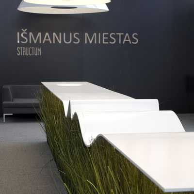 Wavy presentation desk from white acrylic solid surface hanging in the air above the grass / fabricator - Gforma