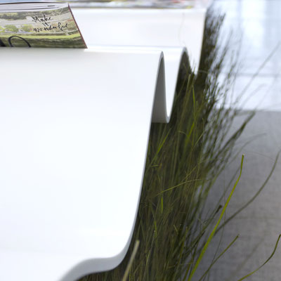 Wavy presentation desk from white solid surface that optically looks like hanging in the air over the grass / fabricator - Gforma