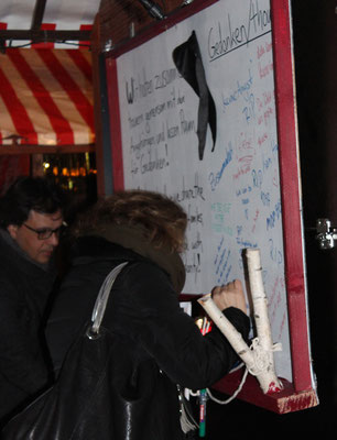 Eine Frau schreibt auf ein Plakat ihre Gedanken zum LKW-Attentat. Weihnachtsmarkt #Breitscheidplatz. Foto: Helga Karl 20.12.2016