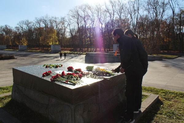 Vandalismus und Grabschändung: zwei Menchen stehen vor der mit Plane abgedeckten und Blumen belegten zerstörten Steinplatte "Die Heimat wird ihre Helden nicht vergessen". Sowjetisches Ehrenmal Treptower Park. Foto: Helga Karl 8. November 2015