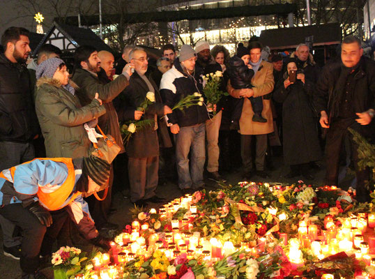 Menschen legen Blumen und brennende Kerzen auf den Boden - am Tag nach dem Attentat eines kriminellen Asylanten mit 12 Ermordeten. Foto: Helga Karl 20.12.2016