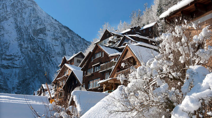 Verschneite Häuser in Hallstatt im Winter mit Bergkulisse im Salzkammergut