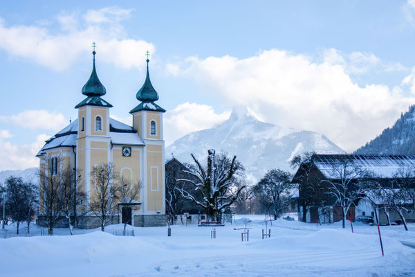 Basilika Mondsee im Winter mit schneebedecktem Ortszentrum und Bergkulisse
