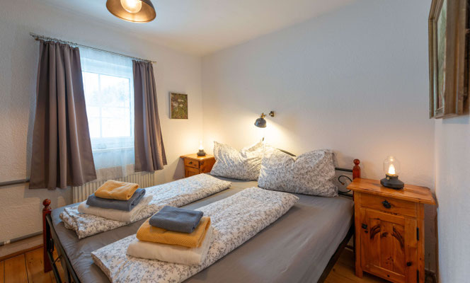 Schlafzimmer in der Ferienwohnung Haus Sonnenschein mit frischer Bettwäsche und Nachttischlampen