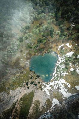 Drohnenaufnahme eines Bergsees im Salzkammergut mit türkisfarbenem Wasser und alpiner Landschaft