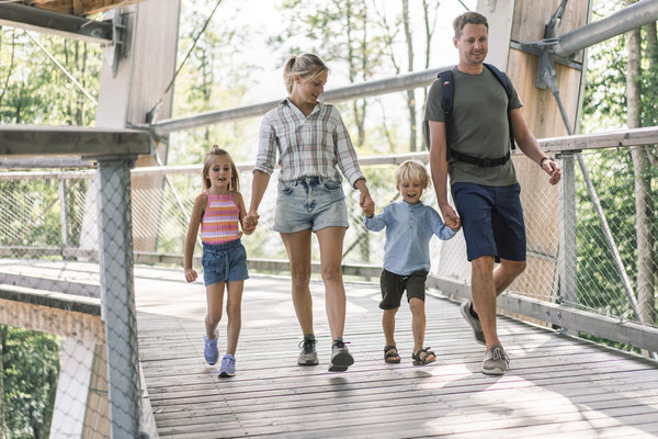 Familie spaziert über einen Holzsteg in der Naturregion rund um den Traunsee im Salzkammergut