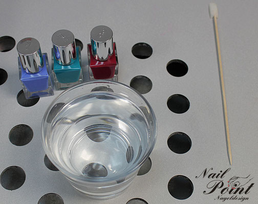 Glas mit destilliertem Wasser und Nagellack in verschiedenen Farben. 