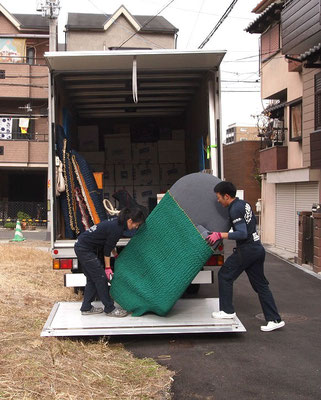 大きな荷物を協力してトラックに載せる