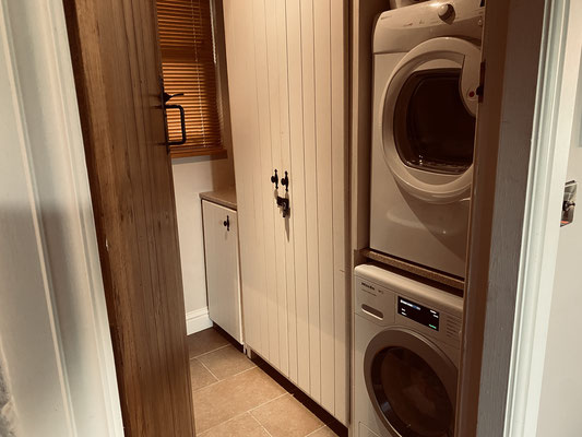 The guests bath room with washing machine and tumble dryer