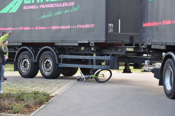 Das Demonstrationsrad gerät durch die Verkleinerung vom Radius unter den Anhänger und wird von dessen Reifen überrollt.