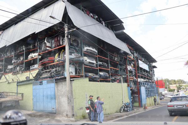 ...still in San Salvador City we see armed civilians in front of a car scrap..
