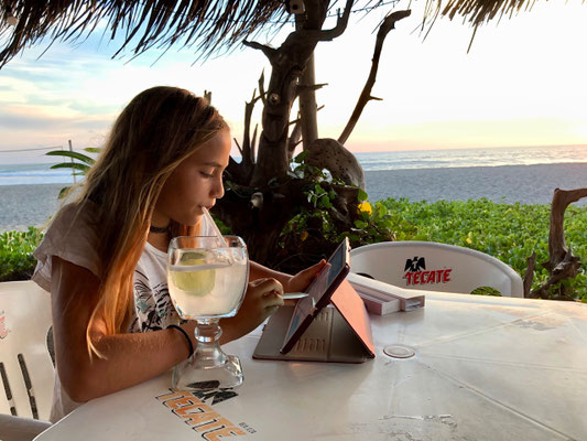 home work at sunset in a beach bar sipping lemonade