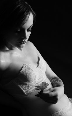 Boudoir im Studio: Frau in weißer Wäsche auf Stuhl, direkter Blick, sanftes Licht.