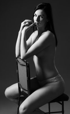 Schwarzweiß: Frau in Dessous sitzt auf Stuhl, klassische Boudoir-Pose, Schattenlicht