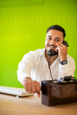 Telefonierender Mann vor grünem Hintergrund in LVM Versicherungsagentur Jürgen März. Business Porträt, aufgenommen von Sebastian Schieder - Fotograf Regensburg.