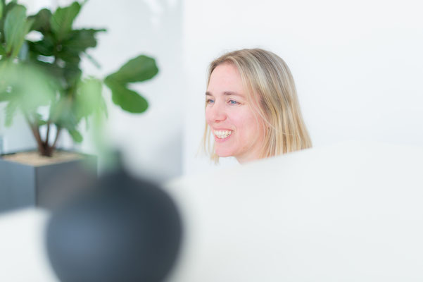 Lächelnde Frau an einem Büro Schreibtisch. Business Porträt, aufgenommen von Sebastian Schieder - Fotograf Regensburg.