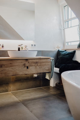 Design Waschtisch aus Eiche mit Aufsatzwaschbecken und an der Wand hängend in einem Badezimmer mit Betonfliesen