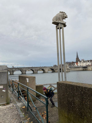 ThP 221219 Maastricht - Aad midden op de GHL3 en ik-Thea als fotograaf idem. Op zijn zuil geeft de Leeuw aan dat hier de eerste Romeinse brug heeft gelegen. Het 1800 jaar oude origineel is in 1963 op deze plek uit de Maas gebaggerd.
