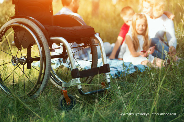 Rollstuhl und Kind mit Behinderung beim Picknick mit der Familie in der Natur